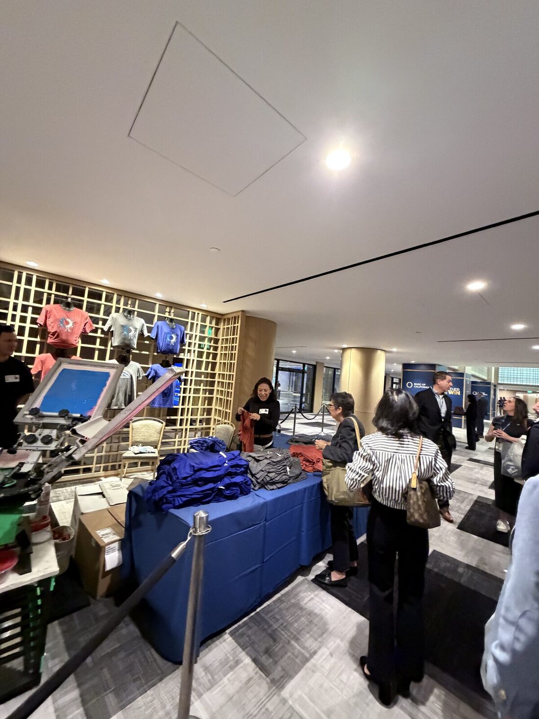 Attendees lined up at a Merch Troop live printing booth on a Chicago trade show floor waiting for custom shirts